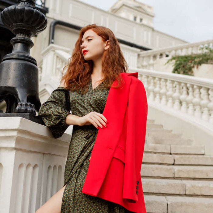 Elegant woman in Italian luxury fashion with a red coat on stairs