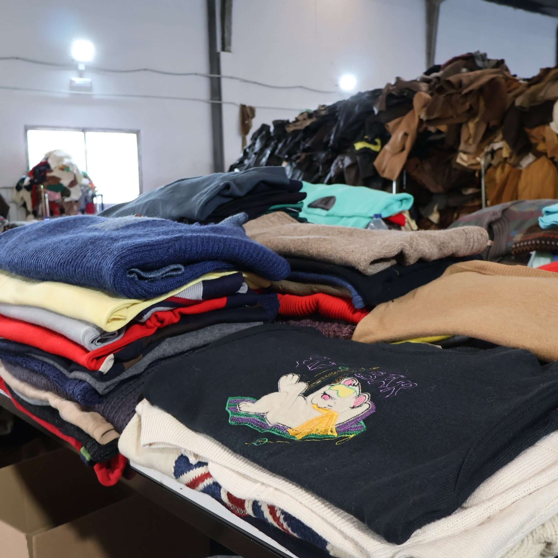 Piles of vintage jerseys and sweaters showcasing various fabrics in a collectible sports apparel store.