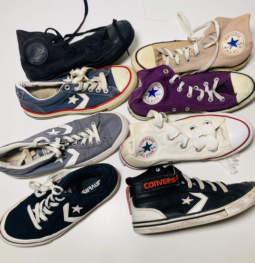 A collection of various Converse sneakers in different styles and colors arranged on a white surface.