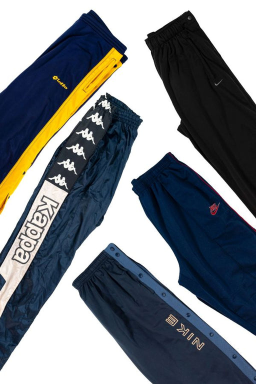 Assorted brand track pants including Kappa, Nike, and others in various colors laid out on a white background.